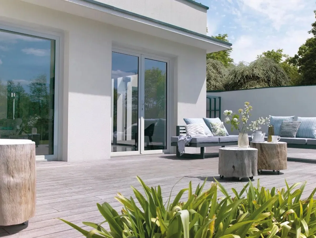 Porte-fenêtre et fenêtre à profilés blancs ouvrant sur une terrasse en bois