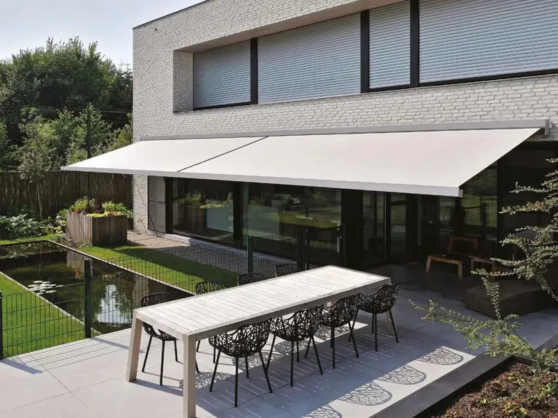 Store banne déployé sur toute la largeur d’une terrasse, table dressée à l’ombre