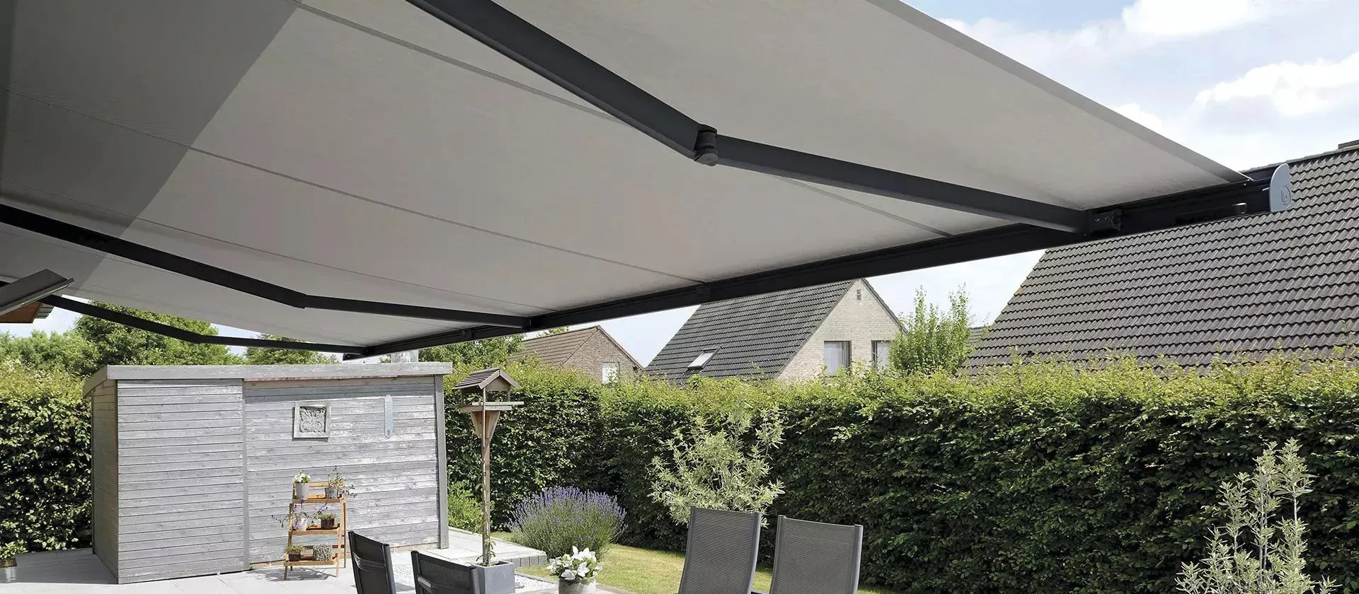 Store banne à coffre intégral déployé au-dessus d’une terrasse exposée au soleil